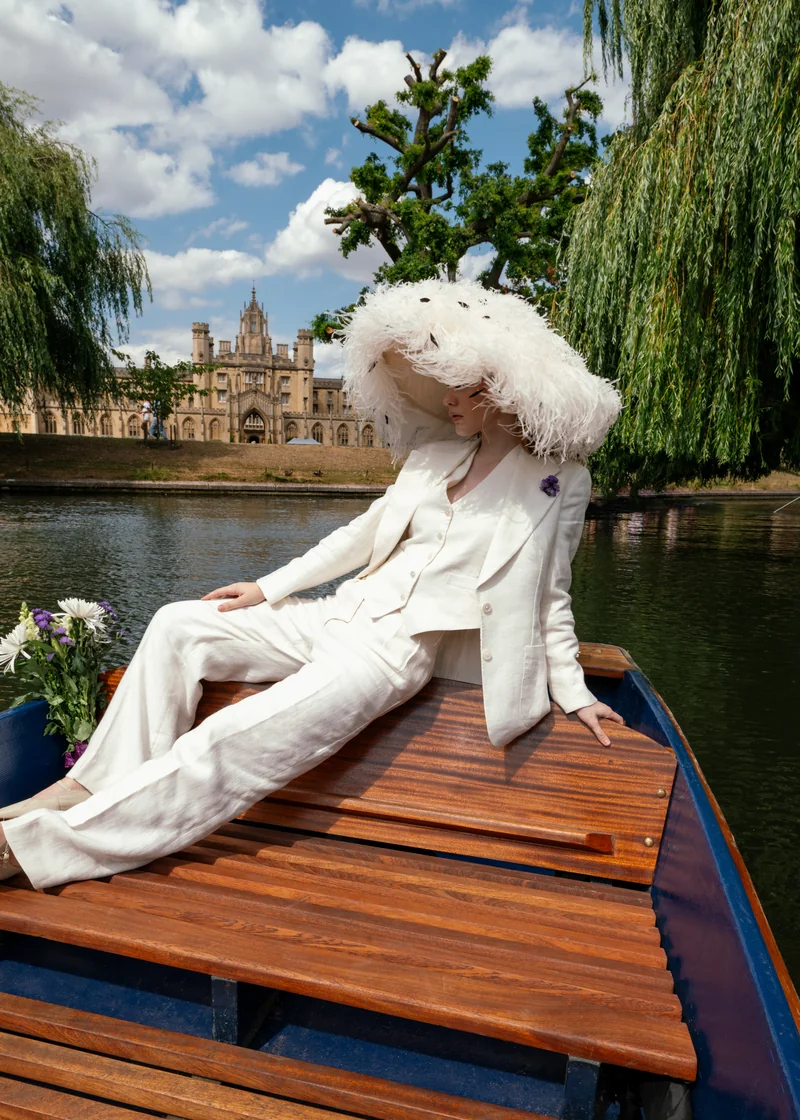 Ivory linen three-piece suit and feathered hat, seated on a punt