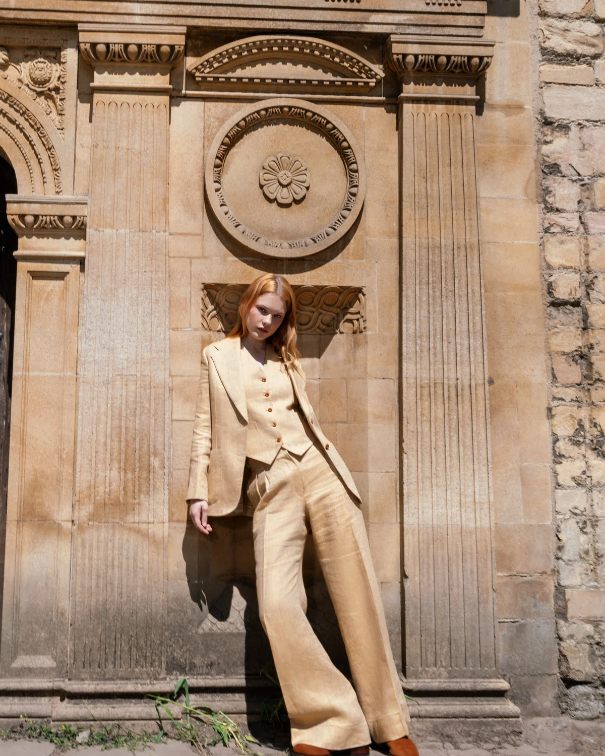 Sand linen three-piece suit against a carved stone gateway