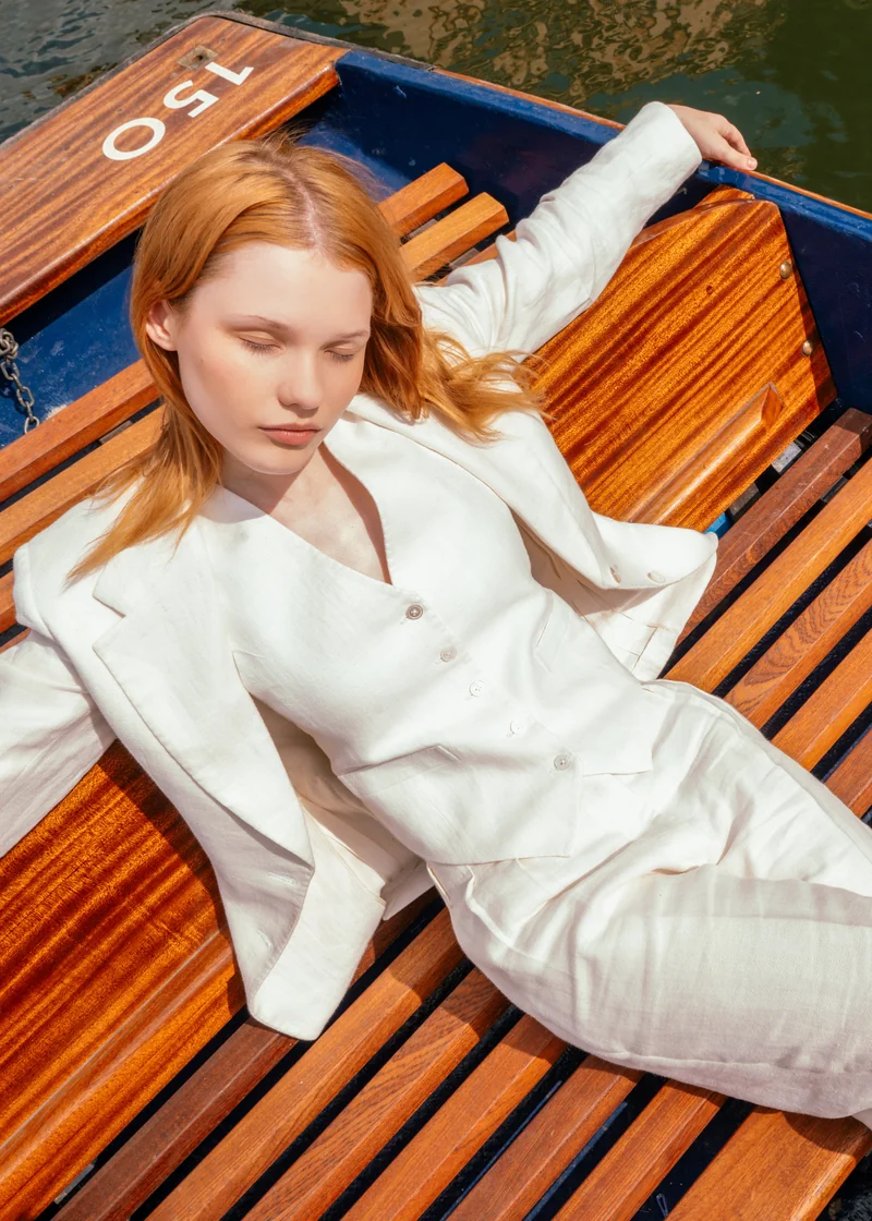 Ivory linen suit, reclining in a wooden punt